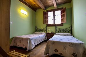 two beds in a room with green walls and a window at El manzano in Castrojeriz