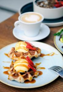 un plateau de gaufres avec des fraises et une tasse de café dans l'établissement Czakó Bed&Breakfast, à Budapest