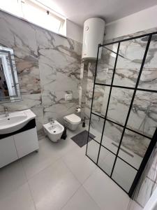 een badkamer met een wastafel, een douche en een toilet bij New Bazaar Studios in Tirana