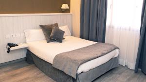 una camera da letto con un grande letto con cuscini sopra di Hotel Coronado a Barcellona