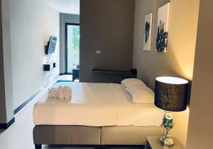 een slaapkamer met een groot wit bed en een lamp bij The Green Plaza Hotel in Bangrak Beach