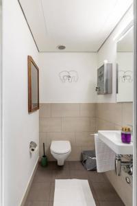 a white bathroom with a toilet and a sink at Designer-Maisonette im Industrie Chic 3,5 Zimmer in Zurich