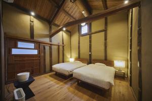 a bedroom with two beds in a room with wooden floors at NIPPONIA 福住 宿場町 in Fukuzumi