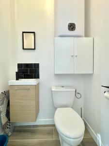 La salle de bains blanche est pourvue de toilettes et d'un lavabo. dans l'établissement Légendes de la piste - SOnights, à Château-du-Loir