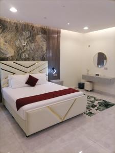 MY HOTEL AL YAQOT 3 POOLS VILLA - NIZWA في نزوى‎: غرفة نوم بسرير ابيض كبير ولوحة على الحائط