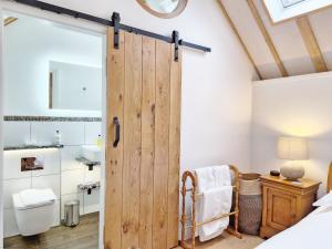 un baño con una puerta corredera de un granero en un dormitorio en Sussex Barns - Horsham en Horsham