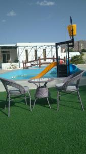 MY HOTEL AL YAQOT 3 POOLS VILLA - NIZWA في نزوى‎: ملعب فيه كرسيين وطاولة