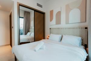 Cozy 1 Bedroom in the heart of Business Bay في دبي: غرفة نوم بسرير ابيض كبير ومرآة