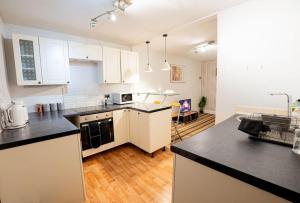 uma cozinha com armários brancos e bancadas pretas em Cosy Canterbury Studio Apartment em Kent