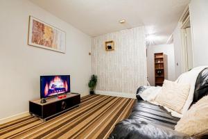 uma sala de estar com um sofá e uma televisão de ecrã plano em Cosy Canterbury Studio Apartment em Kent