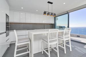 una cocina con sillas blancas y una barra con vistas al océano en Villa Infinite, en Salobreña