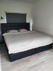 a large bed with a black frame in a bedroom at Nature Zeeland in Lamswaarde