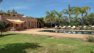 a house with a swimming pool with chairs and umbrellas at Maidan El Arsa in Marrakesh