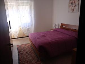 1 dormitorio con cama roja y ventana en La casa di Lucia Appartamento, en Novara