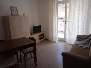 een woonkamer met een bank, een tafel en een televisie bij La casa di Lucia Appartamento in Novara