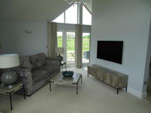 a living room with a couch and a flat screen tv at The Lodge - Bidford Grange Golf Course in Bidford