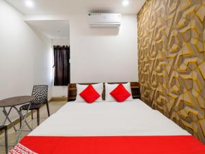 Un dormitorio con una cama con almohadas rojas y una mesa. en Super OYO Flagship Kompally Residency, en Hyderabad