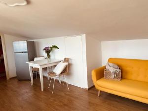 a living room with a table and a yellow couch at La Mansarda degli Ulivi in Portoferraio +18 photos