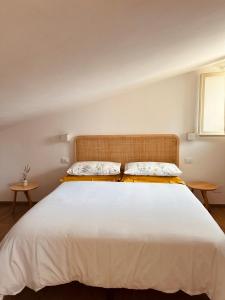 1 dormitorio con 1 cama blanca grande y 2 mesas en La Mansarda degli Ulivi, en Portoferraio