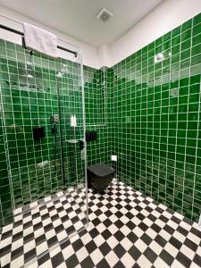 a green tiled bathroom with a toilet and a shower at Maison Frank in Budapest