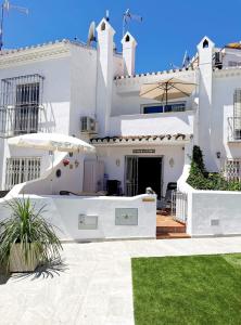 a white house with a patio and an umbrella at CASITA BONITA NERJA in Nerja