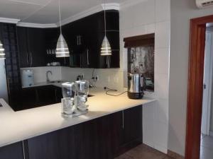 a kitchen with black cabinets and a white counter top at KWR B&B in eMalahleni
