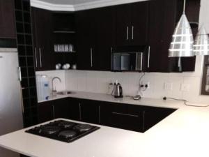 a kitchen with black cabinets and a white counter top at KWR B&B in Witbank