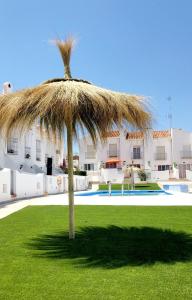 a straw umbrella in a yard with a pool at CASITA BONITA NERJA in Nerja