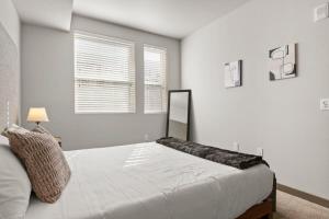 a white bedroom with a bed and a window at Cozysuites PHX RORO Gym Pool Pets Parking #12 in Phoenix
