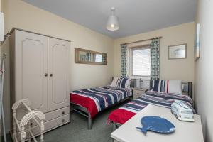 a bedroom with two beds and a table and a table sidx sidx sidx at 34 Llwyn Gwalch in Morfa Nefyn