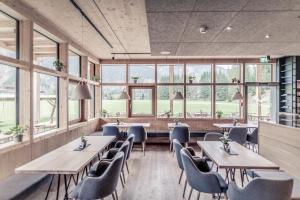 ein Restaurant mit Holztischen, Stühlen und Fenstern in der Unterkunft Boutique Hotel LechZeit in Elmen