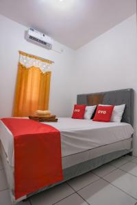 - une chambre avec un lit doté d'oreillers rouges et blancs dans l'établissement Super OYO 92626 Good Sleep 4 Inn Dcos Syariah, à Samarinda