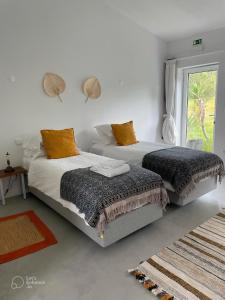 2 camas en una habitación blanca con ventana en Monte da Urze Aljezur en Aljezur