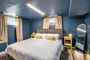 a blue bedroom with a bed and two windows at Large Midtown Home With King Beds, Bunk Room, and Arcade in Omaha