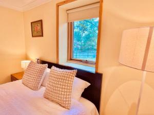 Wonga Park的住宿－Perfect View Retreat in Forest，卧室配有带枕头的床铺和窗户。