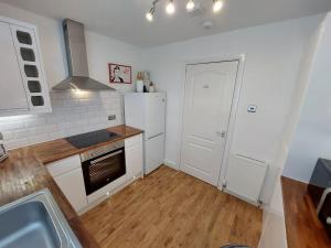 a kitchen with white appliances and a wooden floor at Paisley Pineapple Flat Central UWS Glasgow Airport in Paisley