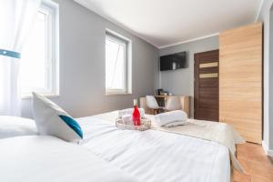 a bedroom with a large white bed and two windows at ReveliQa2 in Pobierowo