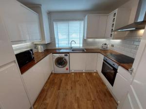 a kitchen with white cabinets and a washing machine at Paisley Pineapple Flat Central UWS Glasgow Airport in Paisley