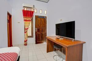 een woonkamer met een televisie op een houten bureau bij OYO 3994 Wisma Amalia in Bandar Lampung
