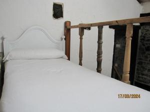 1 dormitorio con 1 cama blanca con marco de madera en La Casina de la Blanea, en Beceña