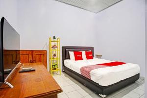 een slaapkamer met een bed, een bureau en een televisie bij OYO 3994 Wisma Amalia in Bandar Lampung