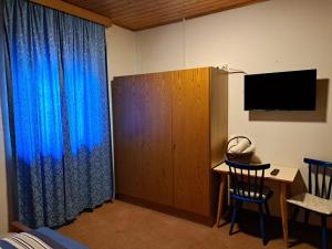 a bedroom with a blue curtain and a desk with a television at Webergütl in Auna di Sopra
