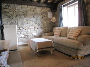 sala de estar con sofá y pared de piedra en La Casina de la Blanea, en Beceña