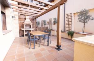 an outdoor patio with a table and chairs and a stove at El sueño del Búho 3. Chimenea y terraza. in Beceite
