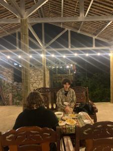 a man and a woman sitting at a table with food at Nhà Cổ Bản Giốc Homestay - Làng đá Khuổi Ky in Bản Piên