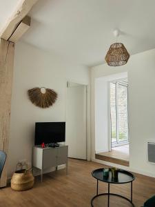 a living room with a tv and a table at Le patio : Appartement chic 3 chambres au cœur de Pau in Pau