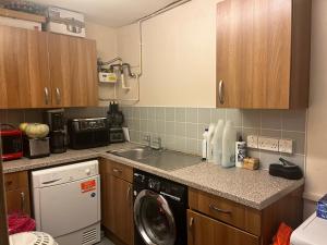 eine Küche mit einer Waschmaschine und einem Geschirrspüler in der Unterkunft Queenomega’s home stay in London