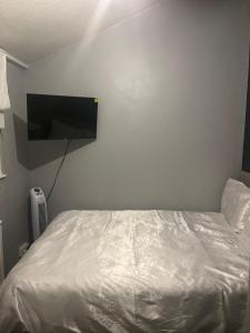 1 dormitorio con 1 cama y TV de pantalla plana en la pared en Queenomega’s home stay en Londres