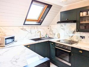 a kitchen with green cabinets and a sink and a window at Lugh 9 - Hot Tub-Perth-Pets-Luxury-Hunting Tower in Perth