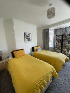 Fionn House Darlington في دارلينغتون: سريرين في غرفة نوم مع ملاءات صفراء